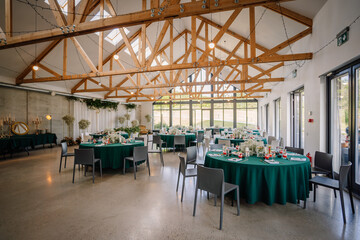 The venue is decorated for a wedding with round tables and green tablecloths, it looks unique and beautiful