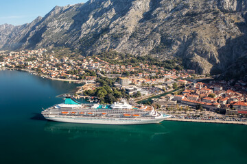 Obraz premium Aerial panoramic view of the picturesque town of Kotor with beautiful coastline, promenade, red roofs, marina with boats and big cruise ship, Montenegro
