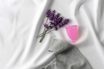 Reusable menstrual cup, lavender and  underwear on white cloth, concept female intimate hygiene...