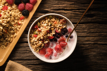 Healthy breakfast. Crunchy oat granola with fresh milk and berries in a white bowl on wooden background.  Dieting and weight loss concept.