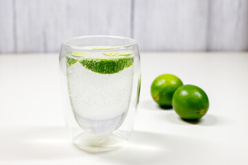 soda water with lime in a transparent glass on the table. quench your thirst in summer
