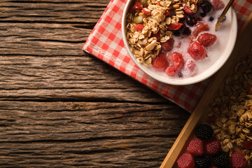 Crunchy oat granola with fresh milk and berries in bowl on wooden background. Healthy breakfast, vegan, dieting and weight loss concept.