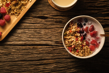 Crunchy oat granola with fresh milk and berries in bowl on wooden background. Healthy breakfast, vegan, dieting and weight loss concept.