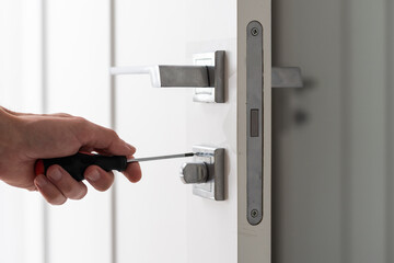Naklejka premium A handyman repair the door lock in the room. The concept repair yourself. Selective focus