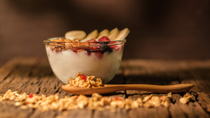 Bowl of yogurt with berries  granola and banana on wooden table. Healthy food, vegeterian, dieting and weight loss concept.