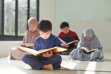 Selective focus of Muslim children reading Koran or Quran together. Focus on little kid sitting in...