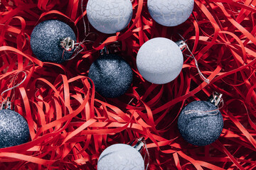 Christmas balls in wrapping paper. Xmas decor on red shredded wrapping paper.