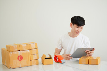 Fototapeta na wymiar Asian young man sitting attentively, carefully checking each purchase order with a sense of pride and responsibility, after successfully launching his own online store.