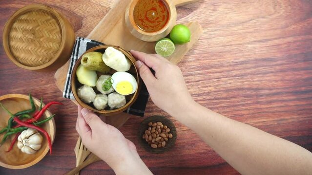 Fish cake dumplings or Siomay is a traditional food from Indonesia made of potato egg cabbage roll peanut chili lime served in a bamboo bowl