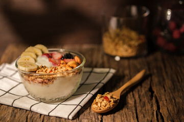 Bowl of yogurt with berries  granola and banana on wooden table. Healthy food, vegeterian, dieting and weight loss concept.