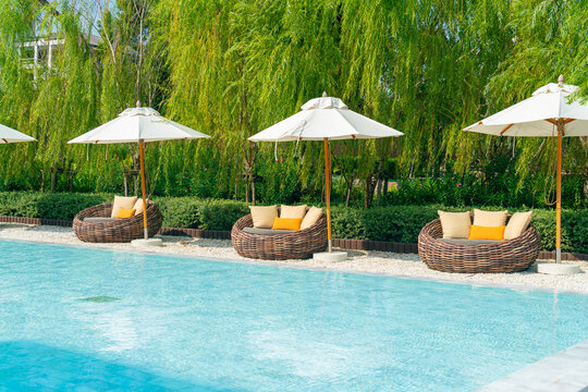outdoor patio chair with pillow and umbrella around swimming pool