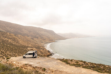 Travelling surfers camp in their van with a dog , campfire and wetsuit, overlooking imsouane, near...