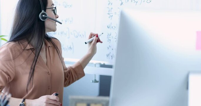 Woman teacher in headphones showing information on blackboard in computer screen 4k movie. Remote education during covid19 pandemic concept
