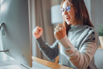 Excited happy asian woman overjoyed get mail at computer being promoted at work, female amazed read good news by computer at home