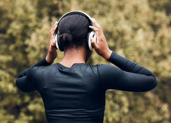 Fitness, back view of woman in woods and with headphones listening to music for workout. Exercise...