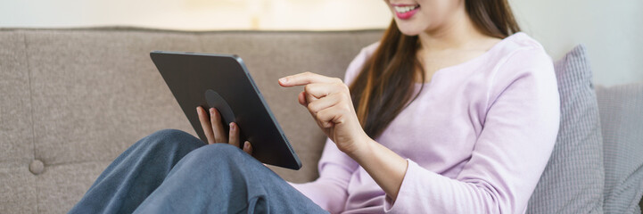 Women sitting on big sofa and using tablet to watching entertainment in lifestyle at home