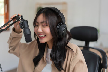 Female podcaster talking about news into microphone and recording audio podcast in broadcast studio