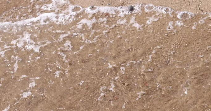 Sea wave washes inscription covid from sand of seashore