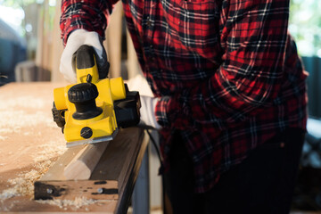 hand holding planing tools A front view of a carpenter wearing a plaid shirt.