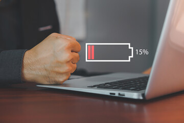 Man is angry and frustrated when he learns that his the laptop computer's battery is dead and did not bring the charger adapter. Concept of Technology and daily life of freelance. No power battery.
