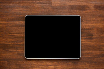 Top view of tablet on the wooden background.