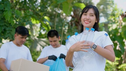 Happy young Asian students diverse volunteers with garbage bags cleaning area in the park, The concept of environmental conservation on world environment day, recycling, charity for sustainability.