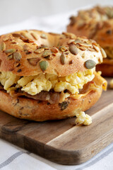 Homemade Bacon, Egg & Cheese Bagel Breakfast Sandwich on a wooden board, side view.