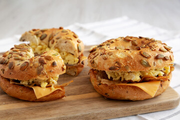 Homemade Bacon, Egg & Cheese Bagel Breakfast Sandwich on a wooden board, side view.