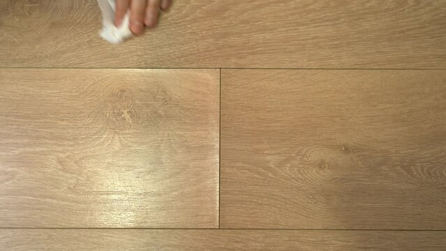 Hand wipes water from swollen laminate floor with napkin and dries with building dryer. Flooding in apartment. Floor water damage