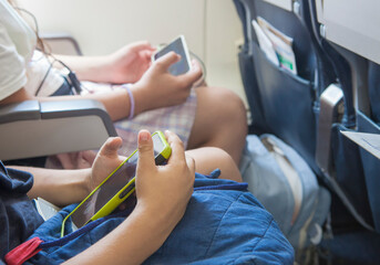 Children watching videos with smartphone in-flight. Young aircraft passengers using their own...