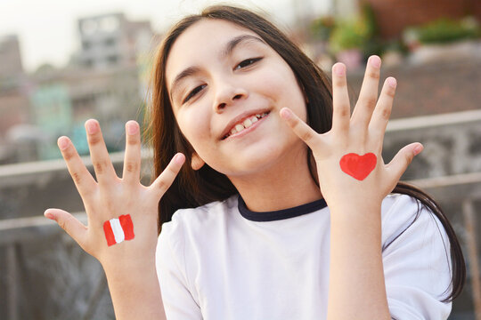 Happy peruvian kid with colors of peruvian flag on the hand.