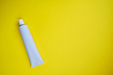 Stylish metal tube for drug or cosmetic branding - cream, gel, skin care, toothpaste. Container for cosmetic bottles on a colored background. Minimalism
