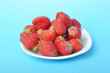 Strawberries on a plate on a blue background