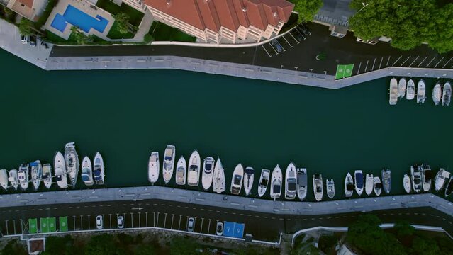 Drone top view shot of marina with boats and houses at small sea village. Real estate for summer vacation. Early morning at port. 