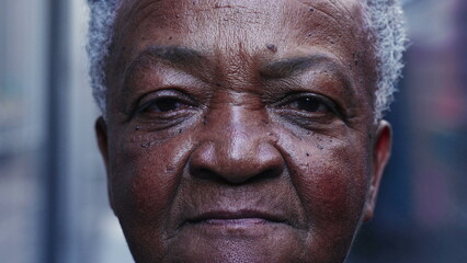Dramatic macro close-up of a senior black woman looking at camera with serious expression. Portrait of a South American elderly lady