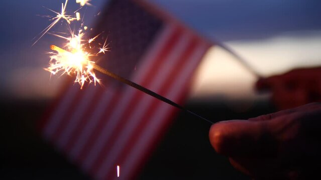 Happy Independence Day July 4th, Labor Day. Hand holding sparklers fireworks celebration fourth of July, 4th of July with America flag background. Concept Holiday, Freedom, Memorial, Veterans Day