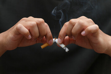 Man holding broken cigarette in hands. Stop smoking cigarettes concept. No smoking campaign concept.