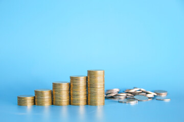 Stacks of golden money coin on wooden desk and blue background with copy space. Minimal stype business background concept. 