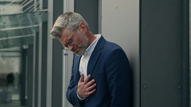 Bad feeling senior old businessman with heart attack need doctor in city suffer with sudden heartache heartburn ill unhealthy unwell business employer man holding chest with pain ache in city outdoors