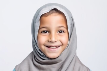 Portrait of a smiling little muslim kid wearing hijab over white background