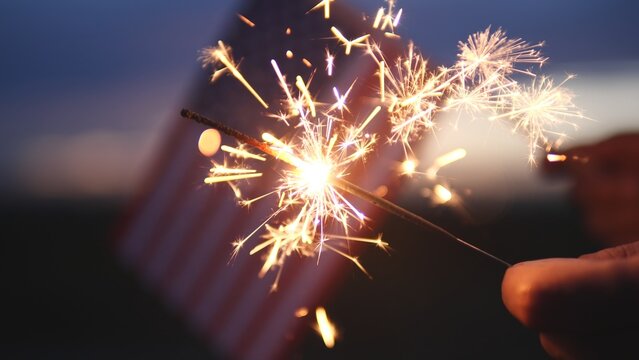 Happy Independence Day July 4th, Labor Day. Hand holding sparklers fireworks celebration fourth of July, 4th of July with America flag background. Concept Holiday, Freedom, Memorial, Veterans Day