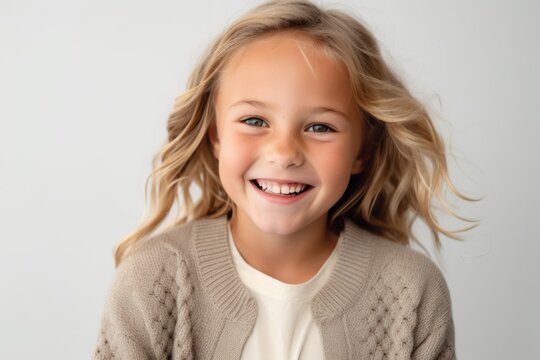 Lifestyle portrait photography of a grinning child female wearing a chic cardigan against a white background