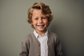 Portrait of a cute little boy with blond hair in a jacket on a gray background