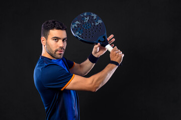 Padel tennis player. Man athlete with paddle tenis racket on black background.