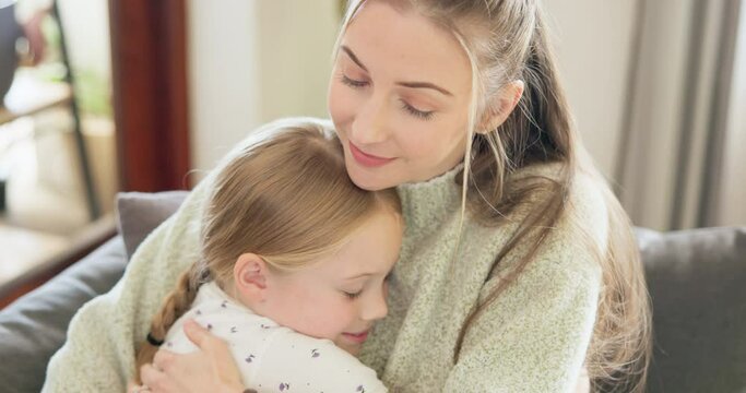 Mom, love and hug girl with a smile or bonding, support and care for child with happiness on living room, sofa or home. Hugging, mother and daughter with happy embrace and quality time together