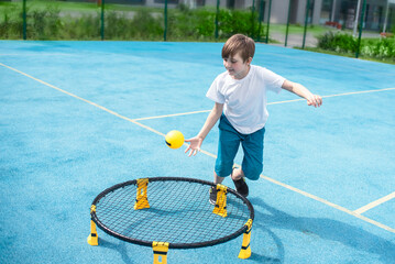 child playing sports game spikeball, spikeball. the boy is hitting the yellow ball in a miniature...