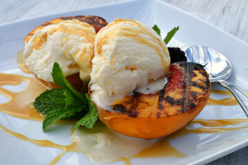 Grilled peaches topped with vanilla ice cream and caramel sauce drizzle. Easy summer picnic dessert. 