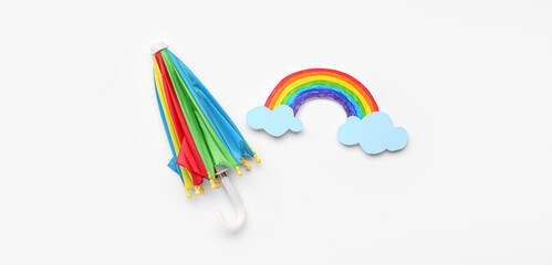 Paper rainbow with clouds and small umbrella on white background. Weather forecast concept