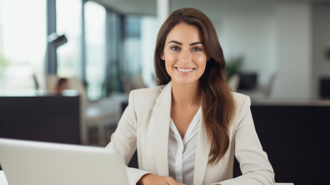 Beautiful happy woman looking at camera while sitting at office