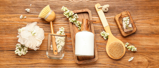 Bottle of liquid soap with serum, massage brushes and bast wisp on wooden background